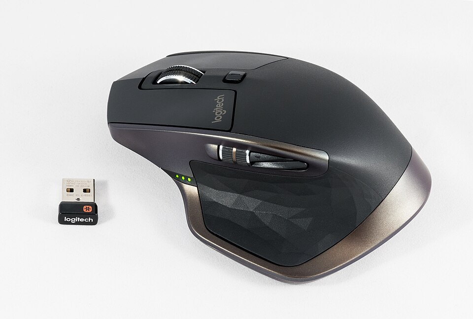 A black computer mouse seen from the thumb side. Two buttons sit on its side, just above where the thumb rests. A small USB receiver lies next to it.
